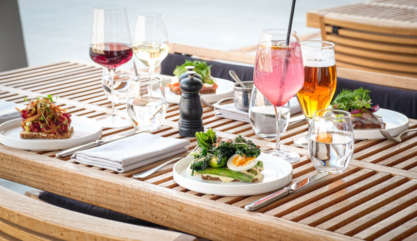 Udendørs spisebord med mad og drikkevarer.